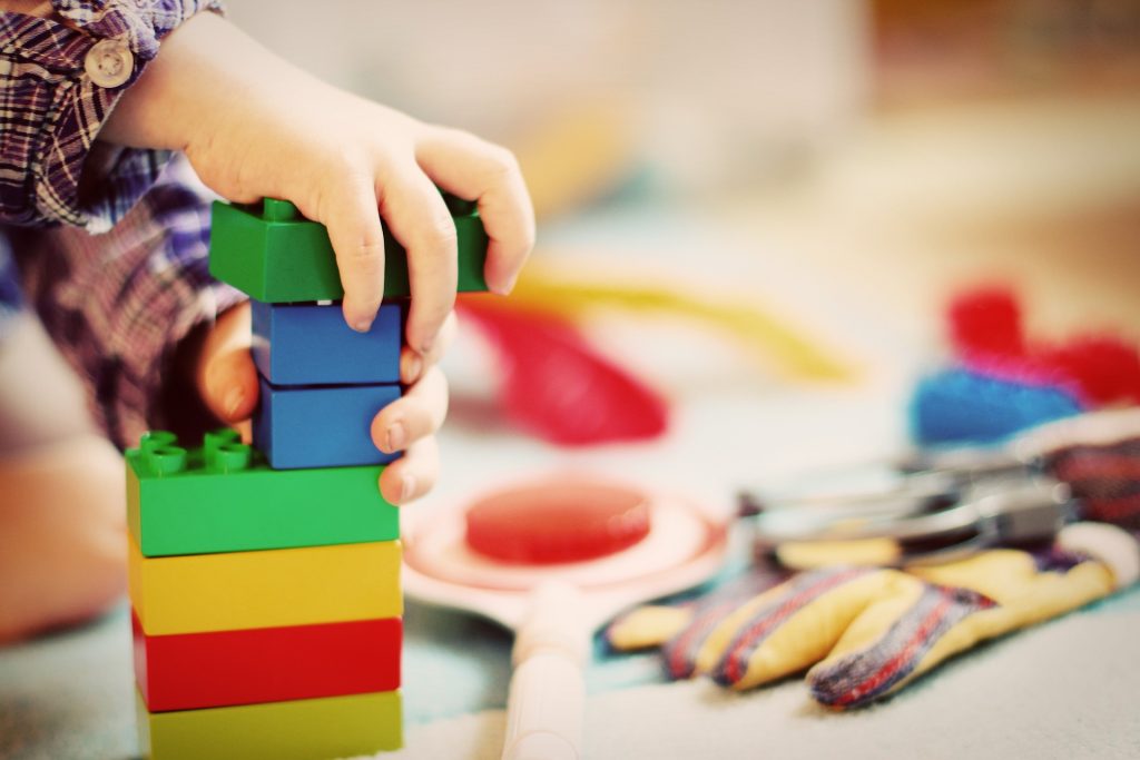Cette image est l'illustration d'un jeune enfant faisant une construction avec des cubes à emboiter